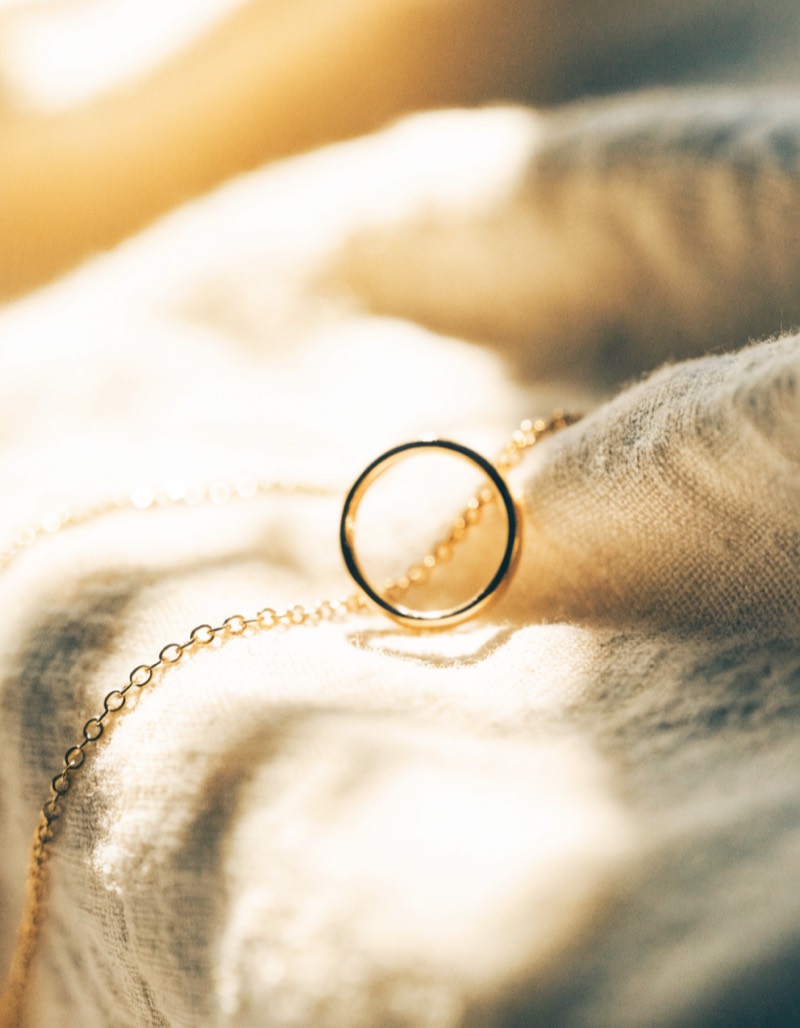 Goldring und feine Kette auf cremefarbenem Leinen